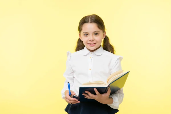 Bambino ragazza uniforme scolastica vestiti tenere libro e penna. Ragazza carina annotare note idea. Note da ricordare. Scrivi un saggio o delle note. Programma personale. Prendo appunti. Bambino uniforme della scuola bambino facendo i compiti — Foto Stock