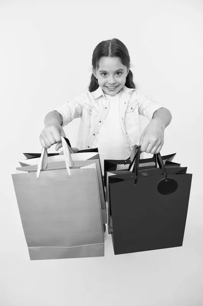 Ελέγξτε έξω την εμπορική πακέτα. Κορίτσι κουβαλάει τσάντες αγορών κίτρινο φόντο. Κορίτσι λάτρης των αγορών. Παιδί χαριτωμένο shopaholic με δέσμη τσάντες αγορών Μαύρη Παρασκευή πώληση συνολικά. Λάβει πακέτα αγορών — Φωτογραφία Αρχείου