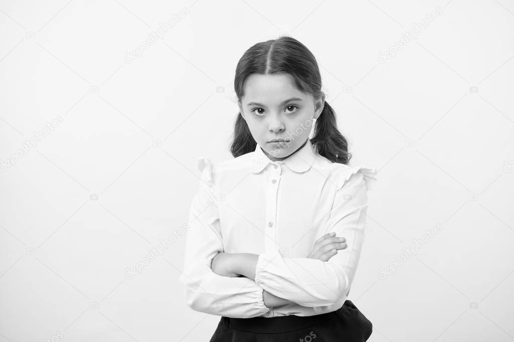Disagreement and stubbornness. Girl school uniform serious face offended yellow background. Kid unhappy looks strictly. Girl folded arms on chest looks serious. Sensitive girl not want to talk