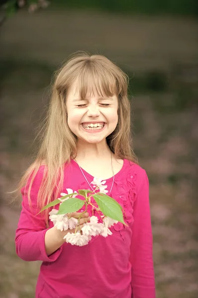 Liten flicka med leende ansikte holding rosa sakura blossom — Stockfoto