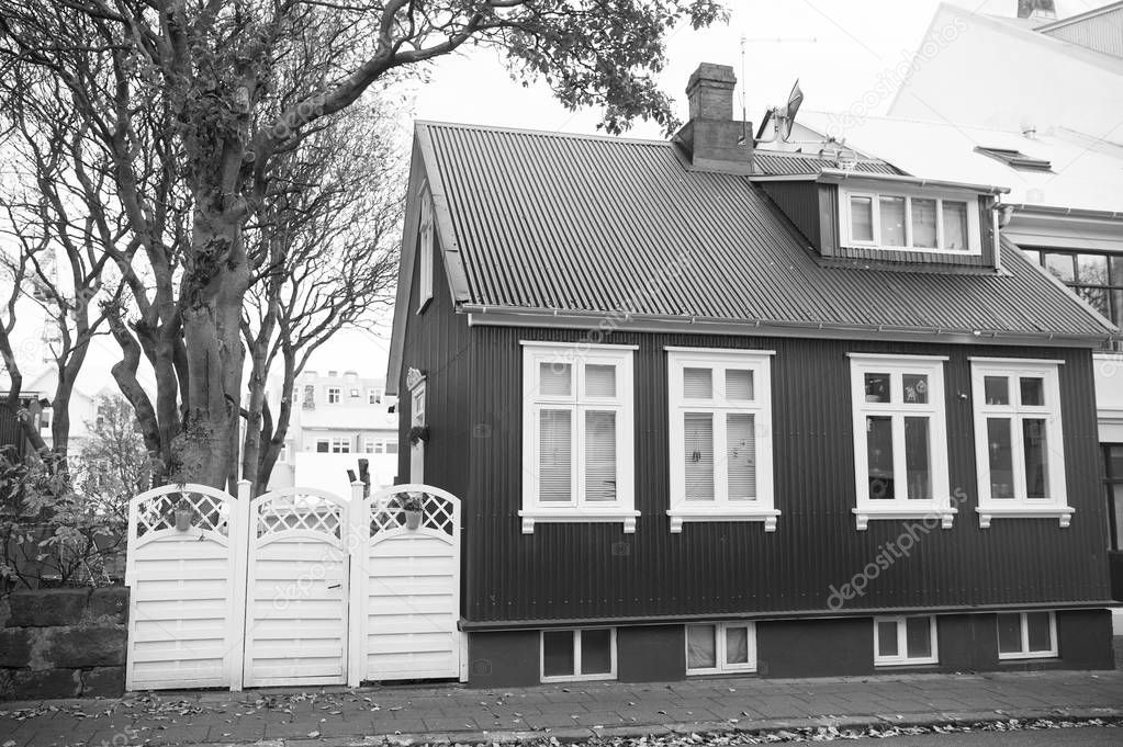 Building facade with red wall and white window frames. Architecture design concept. Scandinavian house design and nordic style. Red stylish house. Bright house at usual scandinavian street cloudy day