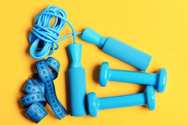 Halter santimetre ve ip atlama ile sarı zemin üzerinde yatıyordu