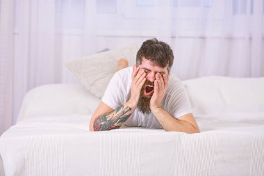 Beyaz çarşaf yatağa kenarında döşeme uykulu esneme yüz adam. Yatak odası konsepti. Adam arka plan üzerinde beyaz perde yatak, döşeme. Maço sakal ve bıyık rahatlatıcı, dinlenme.