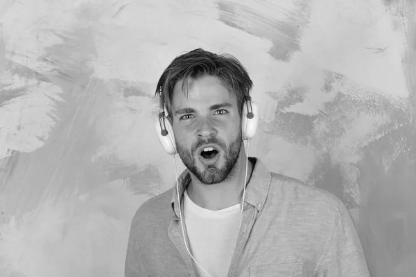 Un bel ragazzo americano con la barba e le cuffie. Stile di vita musicale. Allegro dj adolescente che ascolta canzoni tramite auricolari. Elegante hipster dagli occhi azzurri con smartphone. ragazzo europeo divertirsi tempo — Foto Stock