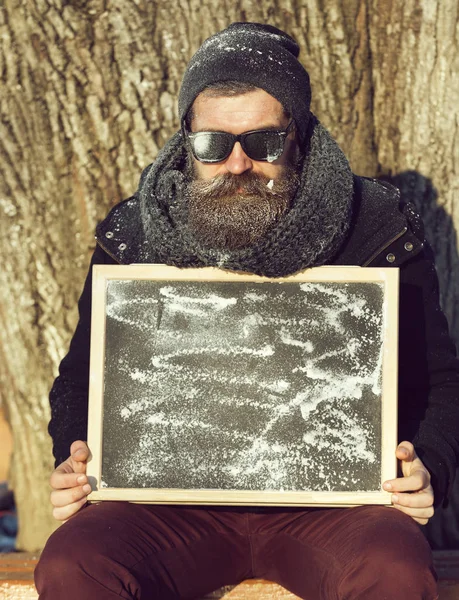 Mannen, ger hipster, med skägg och mustasch i svarta solglasögon täckt med vit frost dubbel ok gest med svarta tavlan på vinterdag på naturlig bakgrund, kopia spac — Stockfoto