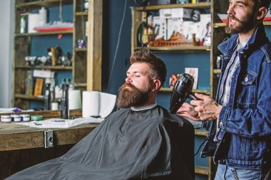Sakallı hippi istemci saç modeli var. Kuaför saç kurutma makinesi ile saç cape dışında kapalı darbeler. Berber kavramı. Kuaför saç kurutma makinesi ile saç modeli sakallı adam, berber arka plan için çalışır
