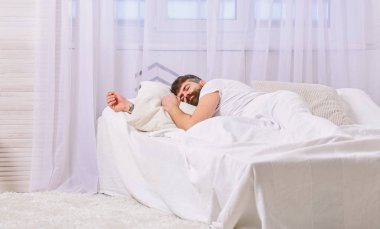 Sakin yüz beyaz çarşafımda yatıyor adam, yastık. NAP ve siesta kavramı. Adam arka plan üzerinde battaniye, beyaz perdeler ile kaplı yatağa atma. Maço sakal uyku ile rahatlatıcı, nap, sahip rest
