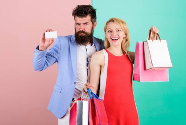 Couple with luxury bags in shopping mall. Couple enjoy shopping. Man bearded hipster hold credit card and girl enjoy shopping. Ask man to purchase lots presents for girlfriend. Paying while dating clipart