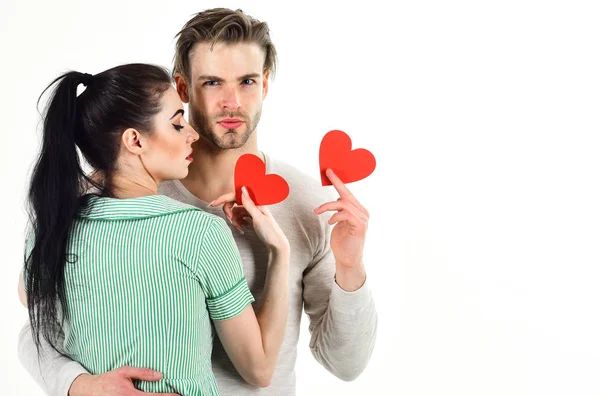 Handsome unshaven man and pretty girl in love. Valentines day and love. Romantic feelings concept. Romantic couple in love hug. Man and woman couple in love hold red heart card on white background — Stock Photo, Image