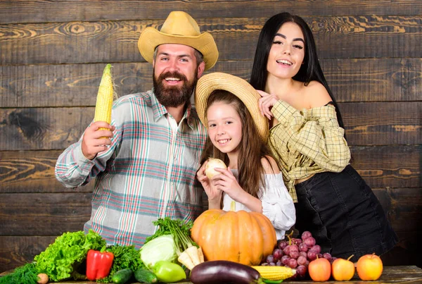 Family farm festival concept. Man bearded rustic farmer with kid and wife. Family father farmer mother gardener with daughter near harvest. Countryside family lifestyle. Farm market with fall harvest
