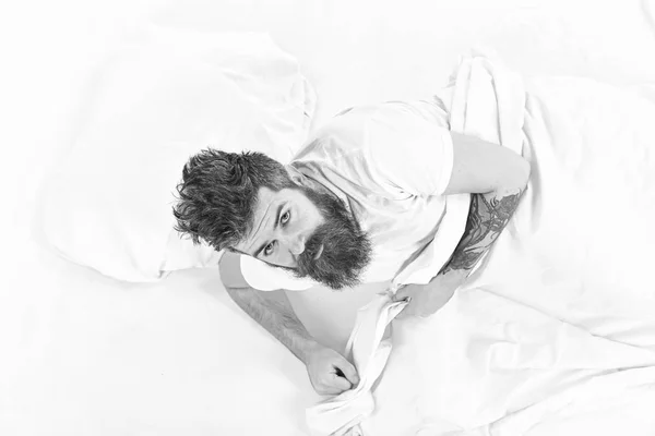 Mann mit verschlafenem Gesicht steht auf dem Bett auf, weiße Laken — Stockfoto