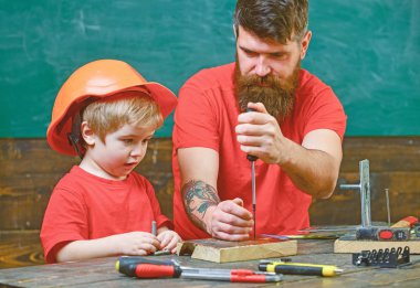 Çocuk, Çocuk koruyucu kask babamla tornavida kullanmayı öğrenme içinde meşgul. Onarım ve atölye kavramı. Baba, sakallı aracı tornavida kullanmak için küçük oğlu öğretim üst