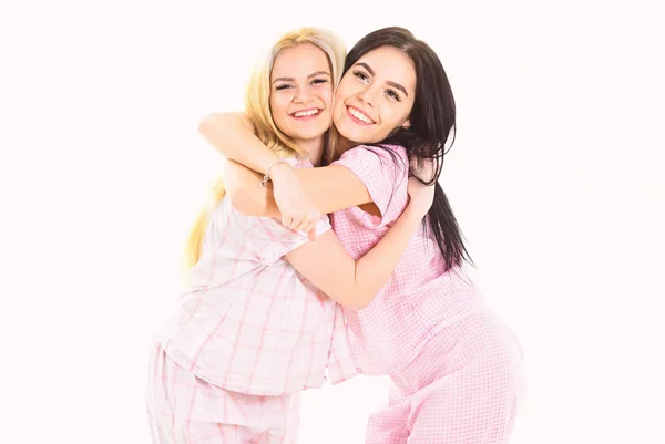 Hermanas o mejores amigas en pijama. Rubia y morena en caras sonrientes en ropa para dormir se ve linda y amigable. Concepto de hermanas mejores amigas. Chicas abrazándose apretado, aislado sobre fondo blanco —  Fotos de Stock