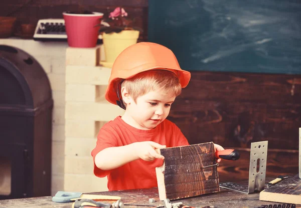 Niño en sombrero duro naranja o casco, fondo de la sala de estudio. Concepto de infancia. Niño soñando con la futura carrera en la arquitectura o la construcción. Niño jugar como constructor o reparador, trabajar con herramientas — Foto de Stock