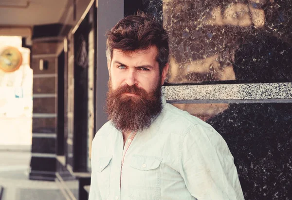 Homem com barba e bigode em rosto estrito, sério ou nojento, fundo de mármore preto. Conceito de masculinidade. Hipster com cabelo desarrumado e barba longa olhando para a câmera — Fotografia de Stock