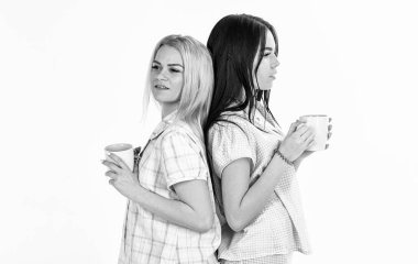 Arka arkaya Sisters veya arkadaşlarım pijama stand. Sarışın ve esmer yüzündeki uykulu kupaları kahve ile tutar. Sabah kahve içme kızlar beyaz arka plan izole. Sabah kahve kavramı