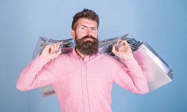 Adam serin öğeler, tatil acele kavramı aranıyor. Üzerinde mavi arka plan izole pembe gömlekli sakallı adam. Metroseksüel Gümüş Hediyelik çanta taşıyan kesilmiş sakallı. Sakallı adam alışveriş hakkında deli