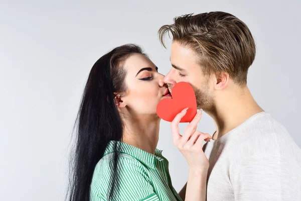 Couple in love kissing and hide lips behind heart card. Celebrate valentines day. Sensual kiss of lovely couple close up. Man and woman romantic kiss. Love and foreplay. Romantic kiss concept — Stock Photo, Image