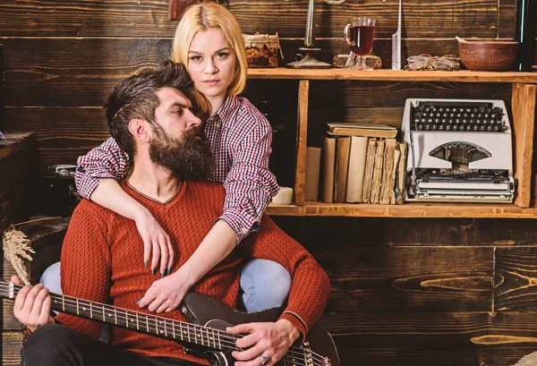 Senhora e homem com barba em rostos sonhadores abraços e toca guitarra. Casal no interior vintage de madeira desfrutar de música de guitarra. Conceito de noite romântico. Casal apaixonado passar a noite romântica em ambiente acolhedor — Fotografia de Stock