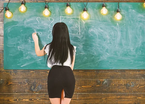 Σέξι δασκάλα στην κοντή φούστα με σκίσιμο εξηγώντας φόρμουλα. Σέξι δασκάλα έννοια. Καθηγήτρια μαθηματικών, γράφοντας στον πίνακα κιμωλίας, πίσω όψη. Γυναίκα με ωραία οπίσθια διδασκαλίας των μαθηματικών — Φωτογραφία Αρχείου