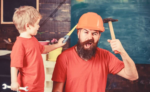 Babalık kavramı. Baba, üst koruyucu kask okul atölyesinde farklı araçları kullanmak için küçük oğlu öğretim içinde sakallı. Evlat, çocuk oyuncakla oynamak neşeli, öğrenme kullanım araçları ile baba gördüm