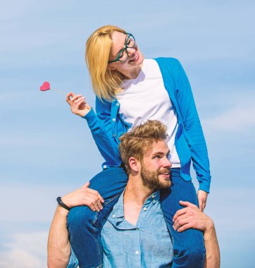 Romantik tarih kavramı. Adam kız arkadaşı omuzlarında, gökyüzü arka plan taşır. Çift mutlu Tarih birlikte eğleniyor. Kadın kalp aşk sopa sembolü üzerinde tutar. İki açık güneşli gün yürüyüş aşk içinde