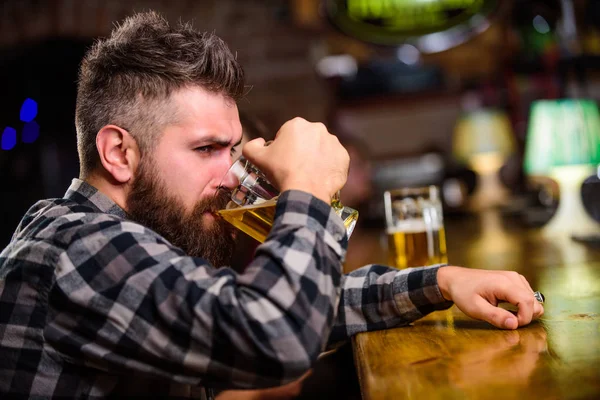 Order alcohol drink. Bar is relaxing place have drink and relax. Hipster relaxing at bar with beer. Man with beard spend leisure in dark bar. Brutal hipster bearded man sit at bar counter drink beer