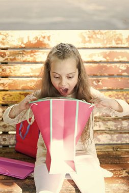 Kız alışveriş torbaları veya hediyeler, arka plan banka açma sürpriz yüzünde. Uzun saçlı hakkında heyecanlı çocuk kız sunar. Sürpriz kavramı. Kız unexpectable hediye veya hediye tarafından sürpriz