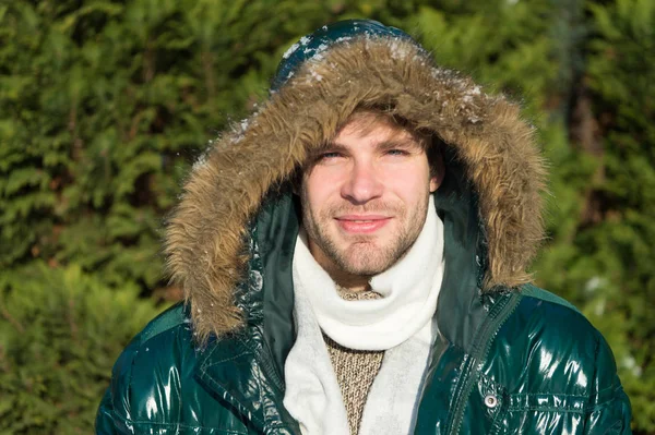 Man unshaven wear warm jacket with fur snowy nature background. Hipster winter fashion. Prepared for weather changes. Winter stylish menswear. Winter outfit. Guy wear winter jacket with furry hood