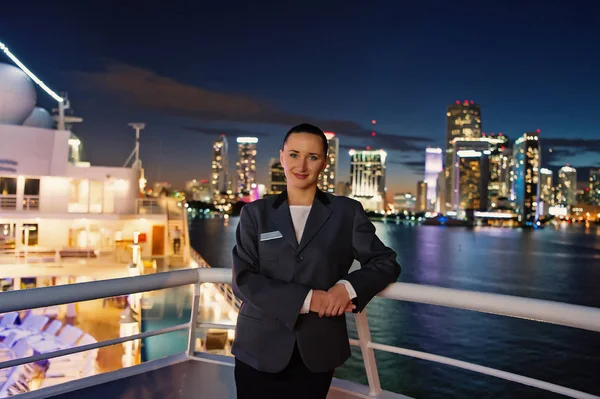 Mujer mayordomo a bordo del barco por la noche en Miami, EE.UU. Mujer sensual en chaqueta de traje en el horizonte de la ciudad. Transporte por agua, transporte. Viajar por negocios. Lujuria, aventura, descubrimiento, viaje — Foto de Stock