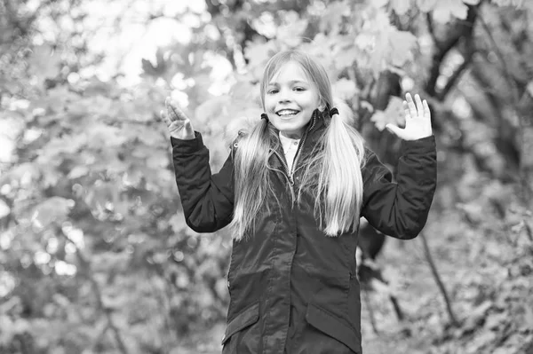 Vrolijke schoolmeisje. Kind blonde lange haren lopen in warme jas buiten. Meisje in de rode jas gelukkig genieten van Val natuurpark. Kind draag modieuze jas met capuchon. Vallen van kleren en mode concept — Stockfoto