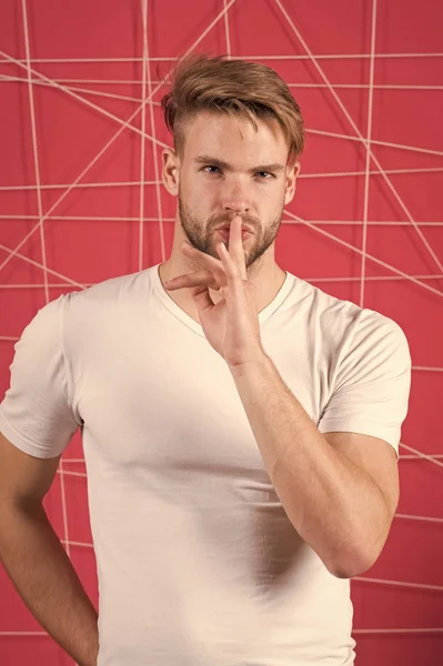 Guy bearded attractive shows silence gesture. Secret concept. Man with bristle strict calm mysterious face, pink background. Man with beard unshaven guy looks handsome well groomed and confident