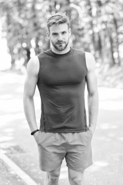 Refah ve sağlıklı vücut keyfini çıkarın. Adam sportif kıyafeti kendine güvenen açık havada doğa arka plan görünüyor. Adam kas vücut onun şeklini gurur sakallı. Sporcu zevk kaslı vücudu kendisiyle gurur