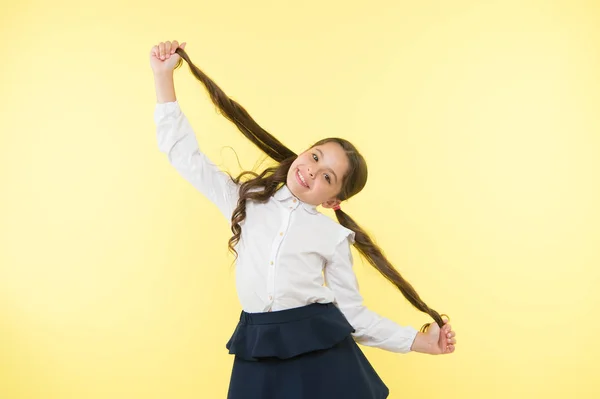 Tratar con peinado de pelo largo por sí mismo. Peinado de niña de cola de caballo larga. El uniforme escolar infantil hace peinado. Niño elegante de moda posando mantener colas de caballo peinado. Peinado cómodo y fácil — Foto de Stock