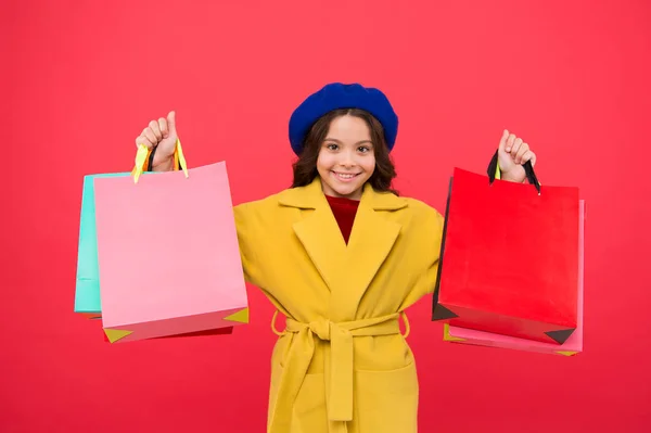 Ottenere grande guardaroba rinfrescare con vendite primaverili nei negozi. Ragazza carino bambino tenere borse della spesa sfondo rosso. Ottenere lo shopping sconto in vacanza di compleanno. Fashionista adorano lo shopping. Ossessionato con lo shopping — Foto Stock