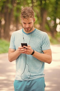 Adam atlet fitness İzleyicisi ile akıllı telefon app, Doğa arka plan kurma meşgul yüz. Sporcu pedometre gadget ile eğitim. Atlet fitness izci veya adım sayar. Spor araç konsepti