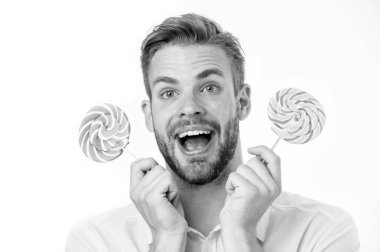 Etkileyici gerçek şeker besin. Yakışıklı sakallı adam lolipop şeker tutuyor. Lolipopu olan adam şaşırmış görünüyor. Sağlıklı beslenme ve diyet konsepti. Şaşırtıcı etki şekerim. Tatil tatlıları.