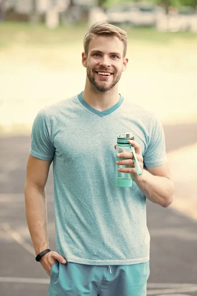 Biraz su iç. Atletik görünümlü bir adam su şişesi adamı spor kıyafetlerini ferahlatıyor. Spor ve sağlıklı yaşam tarzı kavramı. Sporcu, güneşli stadyumda antrenmandan sonra su içer. — Stok fotoğraf