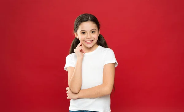 Vrij en blij voelen. Mode meisje op rode achtergrond. Schattig meisje kind in casual stijl. Klein kind met stijlvolle lange haren. Gelukkig klein kind. Fashion look van klein model. Kleine fashionista — Stockfoto