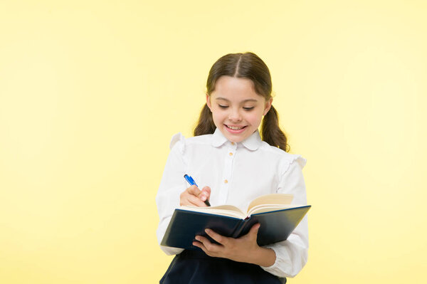 Making notes. Child school uniform kid doing homework. Child girl school uniform clothes hold book and pen. Girl cute write down idea notes. Notes to remember. Write essay or notes. Personal schedule