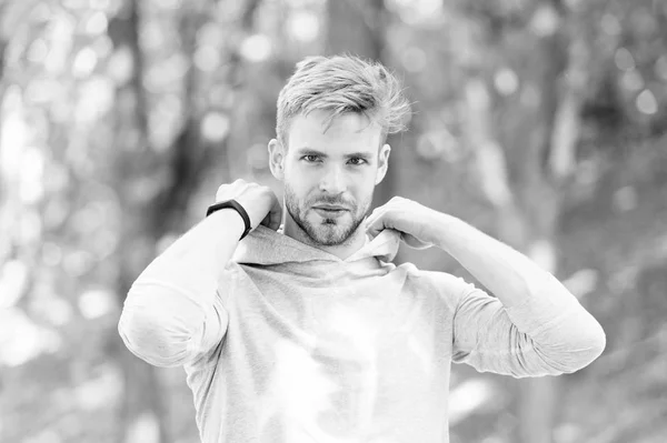 Guy bearded attractive casual put hood on . Man with bristle smiling face nature background defocused. Man unshaven guy looks handsome casual hooded. Comfortable clothing. Feeling comfortable