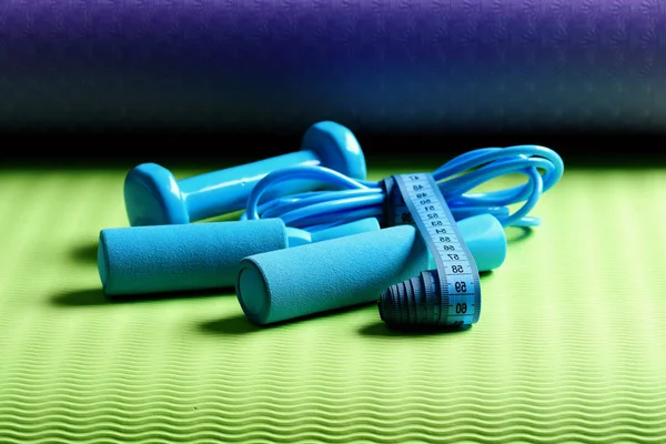 Skipping rope, dumbbells in cyan color tied with measuring tape