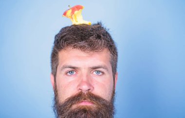 Adam yakışıklı hipster uzun sakal neredeyse kafasına elma güdük hedef olarak yem. Kilo kaybı gol. Hipster sakin yorgun yüz baş mavi arka plan, elma güdük hedef ile kapatın. Canlı hedef kavramı