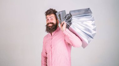 Hippi üzerinde yüz alışveriş göz kırpıyor. Adam alışveriş satış sezonu üzerinde omuz grup taşır. Sakal ve bıyık tutan alışveriş torbaları, gri arka planı olan adam. Alışveriş kavramı