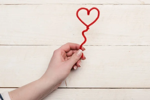 Female hand holding red fuzzy wire heart, top view — Stock Photo, Image