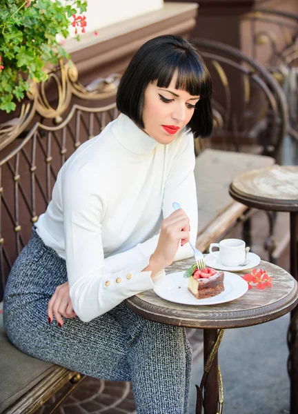 Delicious gourmet cake. Woman attractive brunette eat gourmet cake cafe terrace background. Gastronomical enjoyment. Girl relax cafe with cake dessert. Pleasant time and relaxation. Gourmet concept