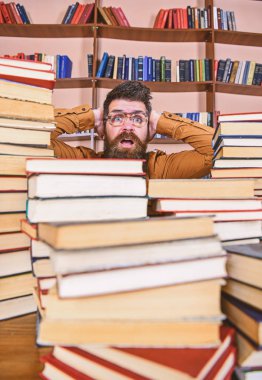 Öğretmen ya da öğrenci sakallı gözlük takmaz, defocused kitaplar ile masada oturur. Adam kazık kitap kütüphane, kitap rafı arka plan üzerinde arasında şok yüzünde. Bilimsel bir keşif kavramı
