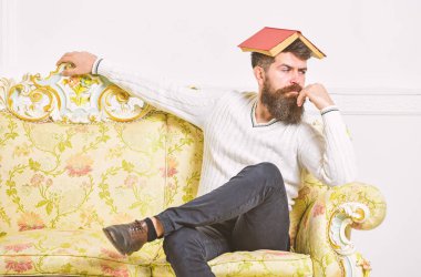 Maço kafasına, çatı gibi açık kitap ile oturuyor. Sıkıcı edebiyat kavramı. Eski sıkıcı kitap okuma fed yukarıya adam sıkılmış. Sakal ve bıyık oturur barok tarzı kanepe, beyaz duvar arka plan üzerinde olan adam