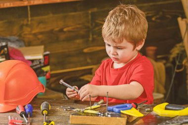 Yürümeye başlayan çocuk meşgul yüzündeki evde atölyede civata ile oynuyor. Kavram handcrafting. Çocuk Çocuk tamirci oynamak. Çocuk şirin ve sevimli ile oynarken Oluşturucusu'nu veya repairer, onarımı veya handcrafting cıvata