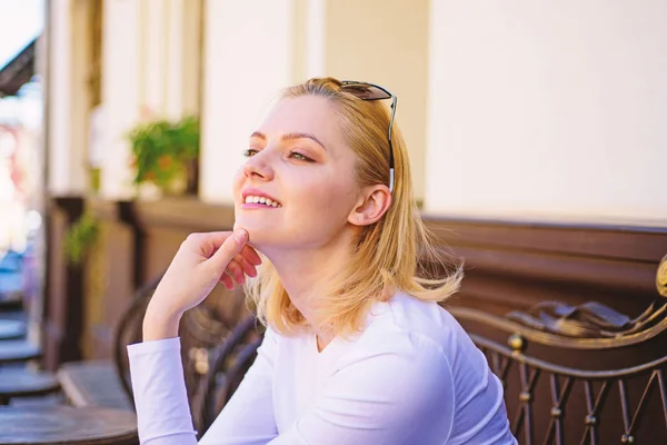 Pleasure on her mind. Woman blonde dreamy smiling face outdoors, building background defocused. What do girls dream about. Lady happy dreaming while relaxing cafe terrace. Pleasant thoughts